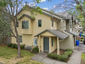 Two-story townhomes with yellow siding, gabled roofs, and landscaped walkways at Roberts Court Townhomes in Gresham, Oregon