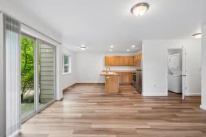 Open kitchen with wood cabinets, sink peninsula, and adjacent laundry closet at Roberts Court Townhomes in Gresham, Oregon