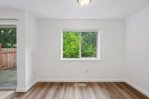 Dining area with greenery-view window, wood-look flooring, and sliding patio door at Roberts Court Townhomes in Gresham, Oregon
