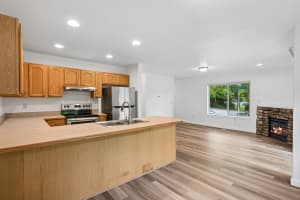 Open kitchen with breakfast peninsula and adjacent stone fireplace at Roberts Court Townhomes in Gresham, Oregon