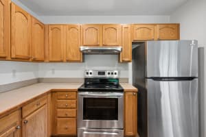Kitchen with arched oak cabinets, beige counters, and stainless steel appliances at Roberts Court Townhomes in Gresham, Oregon