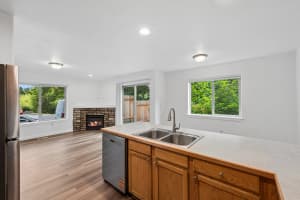 Open kitchen with wood cabinets overlooking a stone fireplace at Roberts Court Townhomes in Gresham, Oregon