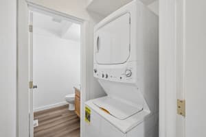 White stacked washer and dryer in a nook beside a bathroom at Roberts Court Townhomes in Gresham, Oregon