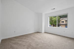 Carpeted bedroom with a large window, blinds, and white walls at Roberts Court Townhomes in Gresham, Oregon