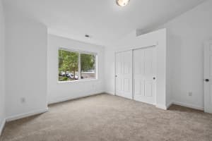 Bright bedroom with vaulted ceiling, beige carpet, and sliding closet doors at Roberts Court Townhomes in Gresham, Oregon