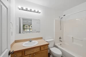 Bathroom with wood vanity, globe lighting, and tub-shower combination at Roberts Court Townhomes in Gresham, Oregon
