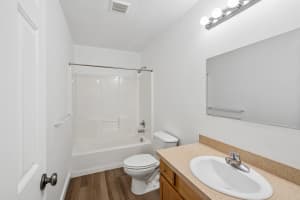 Bathroom with wood vanity, beige countertop, and white tub-shower combination at Roberts Court Townhomes in Gresham, Oregon