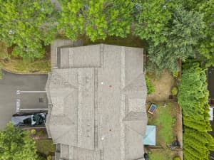 Overhead view of townhome roofs, fenced yards, and mature trees at Roberts Court Townhomes in Gresham, Oregon