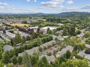Aerial view of townhomes surrounded by mature trees and wooded hills at Roberts Court Townhomes in Gresham, Oregon