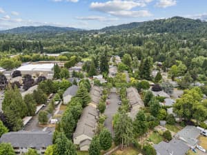 Aerial view of townhome rows surrounded by trees and wooded hills at Roberts Court Townhomes in Gresham, Oregon