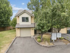 Gabled townhomes with attached garages, mature trees, and community mailboxes at Roberts Court Townhomes in Gresham, Oregon