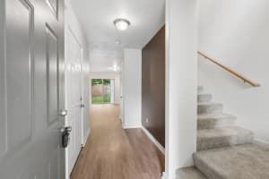 Entry hallway with wood-look flooring, brown accent wall, and carpeted stairs at Roberts Court Townhomes in Gresham, Oregon
