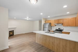 Open kitchen with white peninsula, wood cabinets, and adjacent living room fireplace at Roberts Court Townhomes in Gresham, Oregon