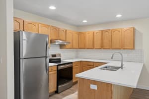 Kitchen with oak cabinets, white peninsula counters, and subway tile backsplash at Roberts Court Townhomes in Gresham, Oregon