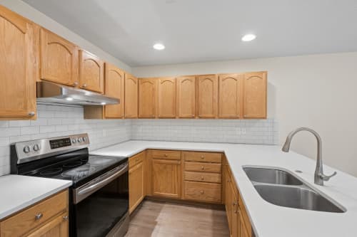 Townhome kitchen with oak cabinets, subway tile backsplash, and stainless steel appliances