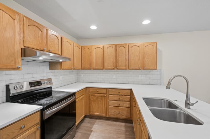 Roberts Court Townhomes kitchen with stainless steel appliances, white countertops, oak cabinets, and subway tile backsplash