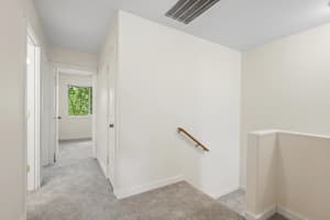 Carpeted hallway and stair landing with a wooden handrail at Roberts Court Townhomes in Gresham, Oregon