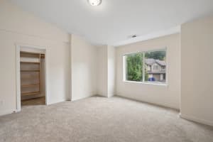 Carpeted bedroom with open closet shelving and a large window at Roberts Court Townhomes in Gresham, Oregon