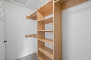 Closet with built-in wood shelving, hanging rods, and carpeted flooring at Roberts Court Townhomes in Gresham, Oregon