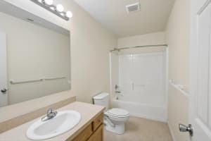 Bathroom with wood vanity, large mirror, and tub-shower combination at Roberts Court Townhomes in Gresham, Oregon