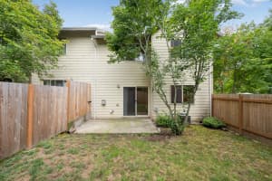Concrete patio with wood fencing, a sliding glass door, and leafy trees at Roberts Court Townhomes in Gresham, Oregon