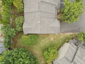 Overhead view of townhome rooftops, mature trees, and grassy green space at Roberts Court Townhomes in Gresham, Oregon