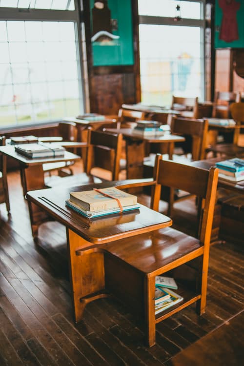 Wooden school desks with books in a sunlit classroom
